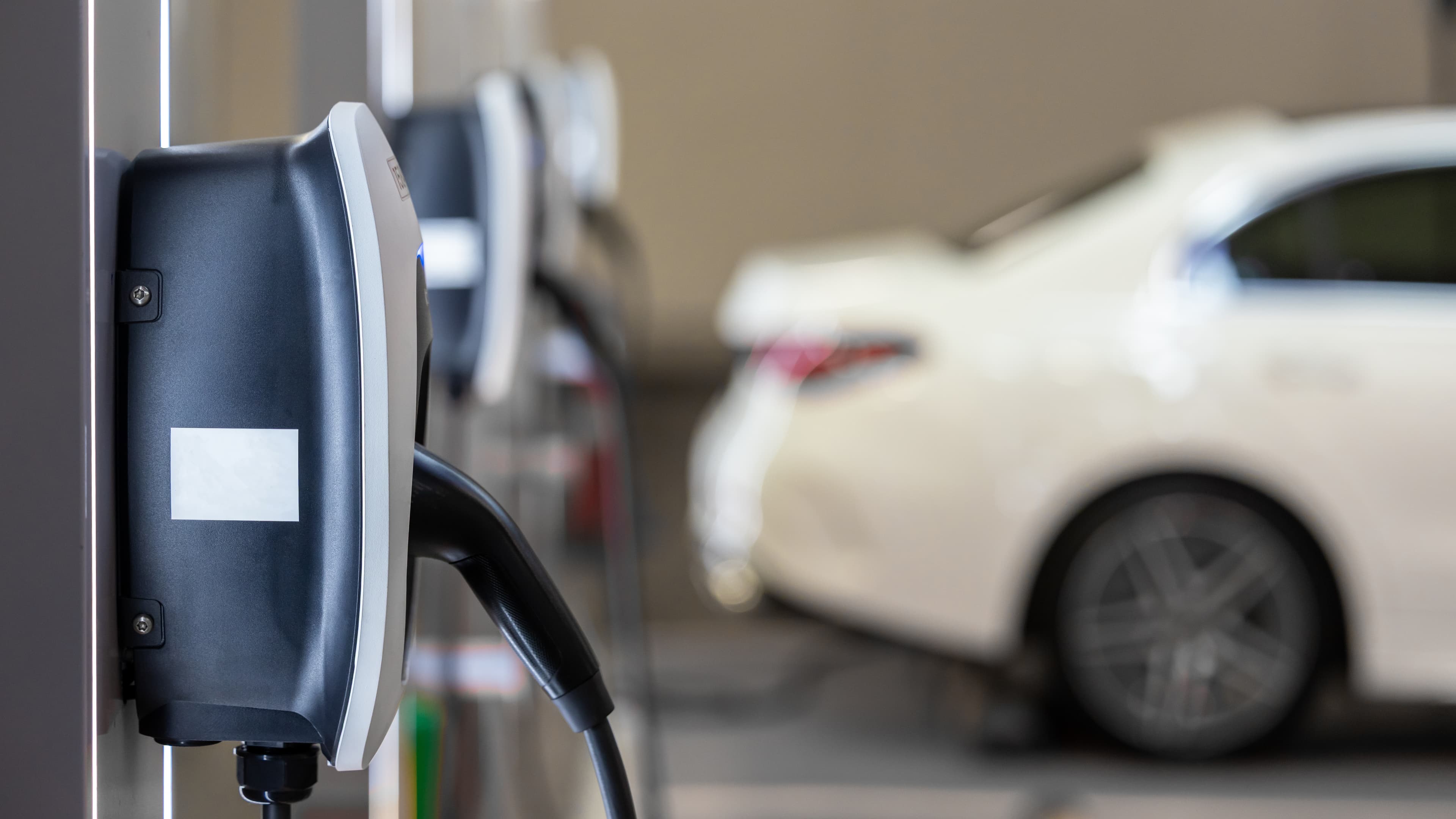 Electric vehicle charger beside a white car