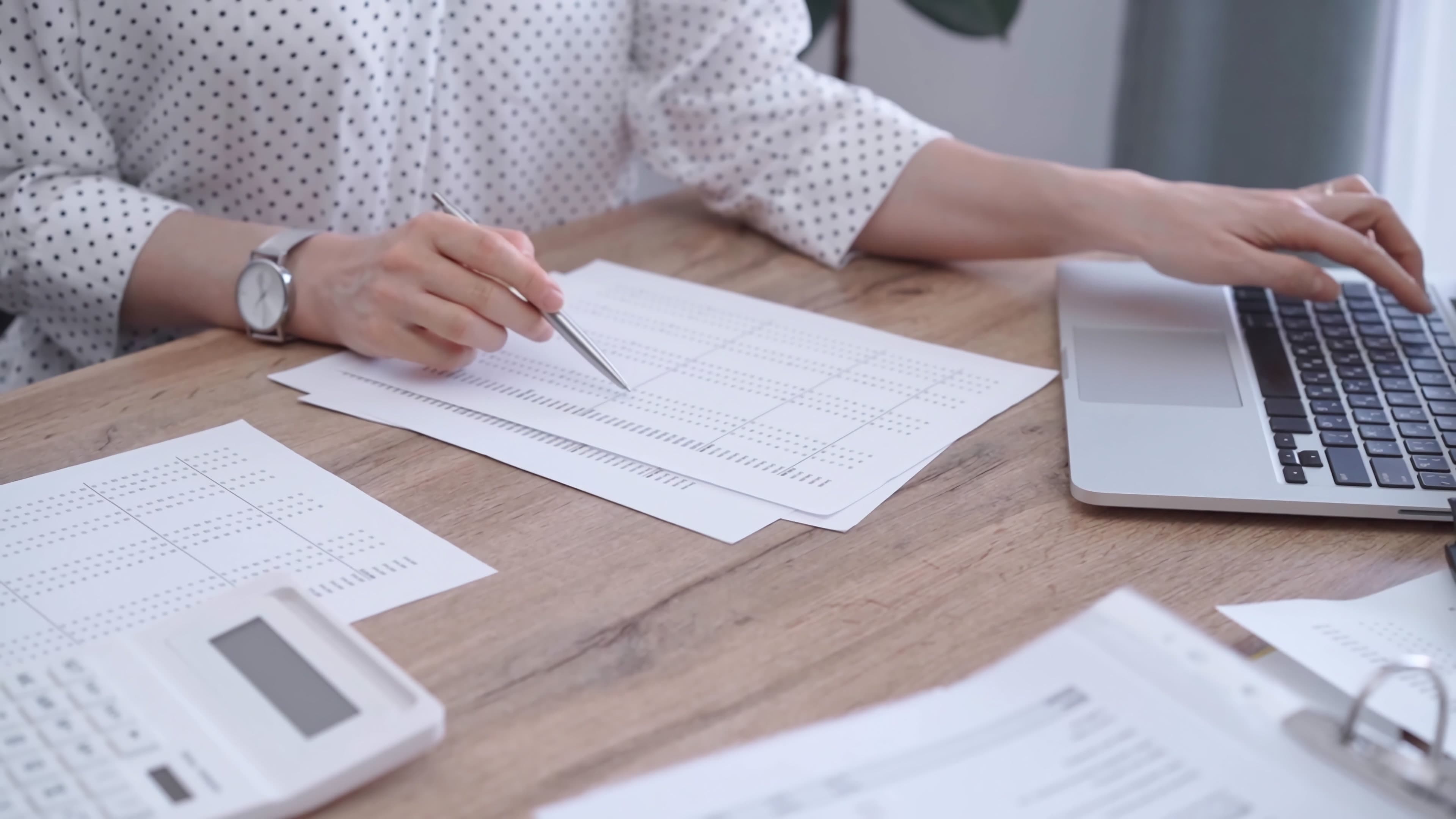 Professional reviewing notes beside a laptop