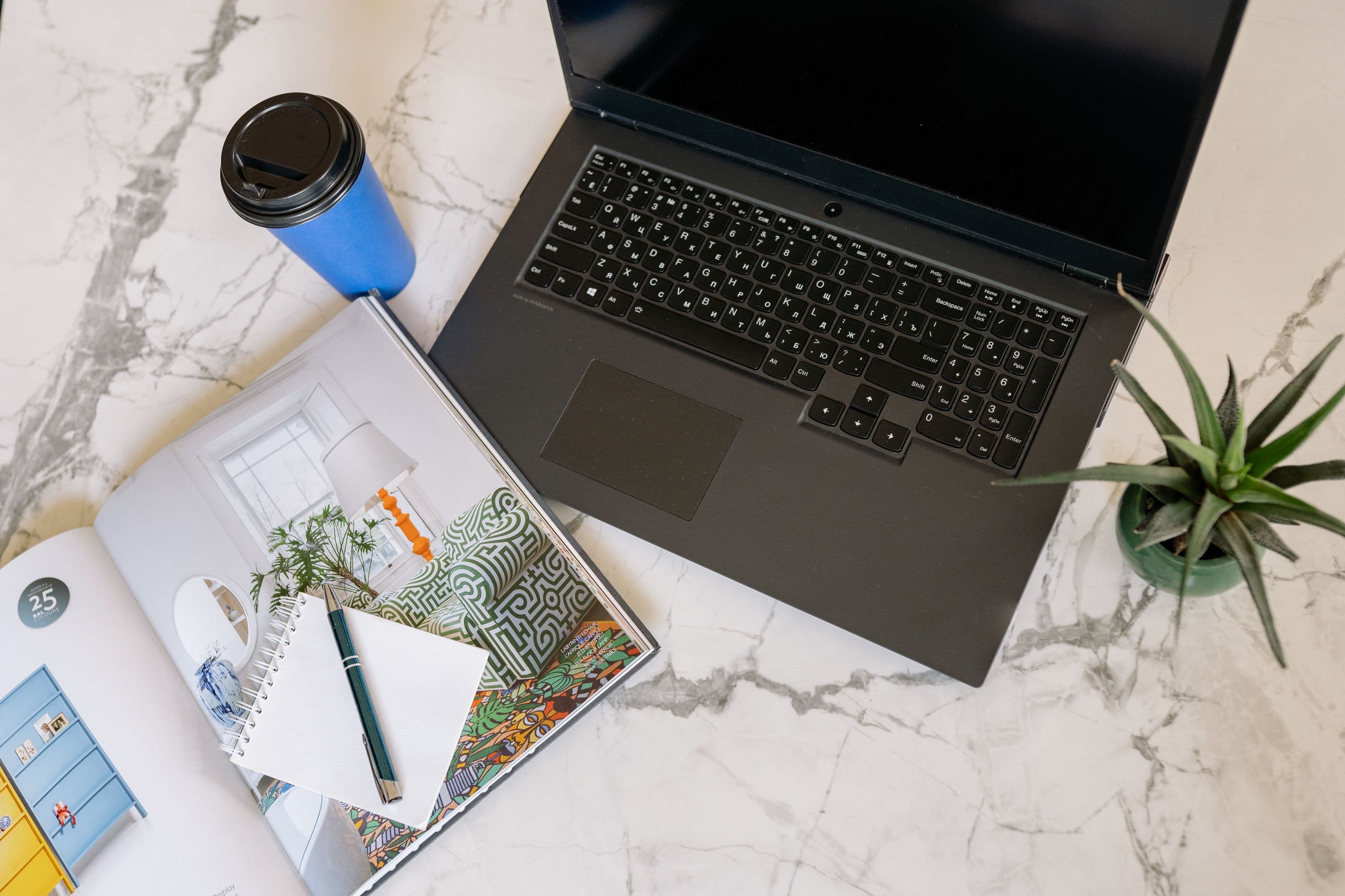 Laptop, notebook, and coffee on a marble desk